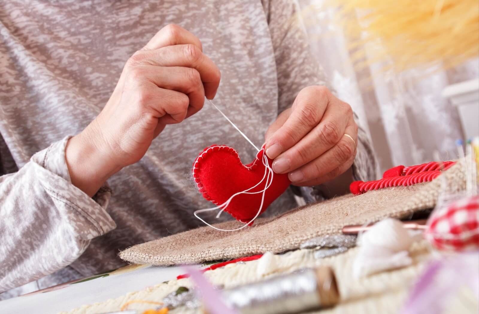 A close-up image of a senior doing a sewing craft.