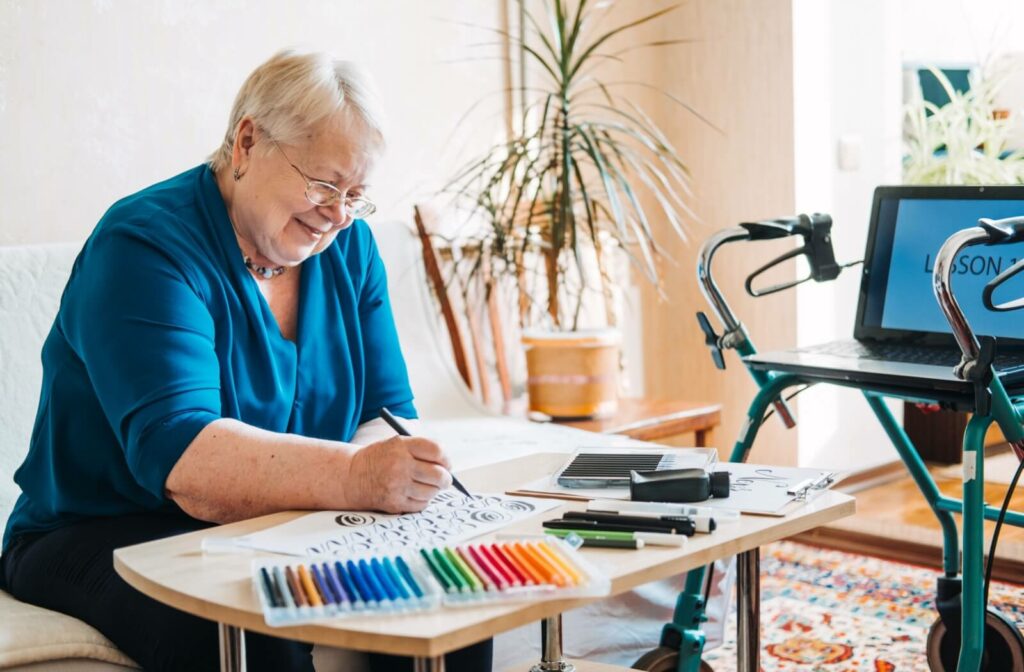 A happy senior uses paint pens to paint a picture.