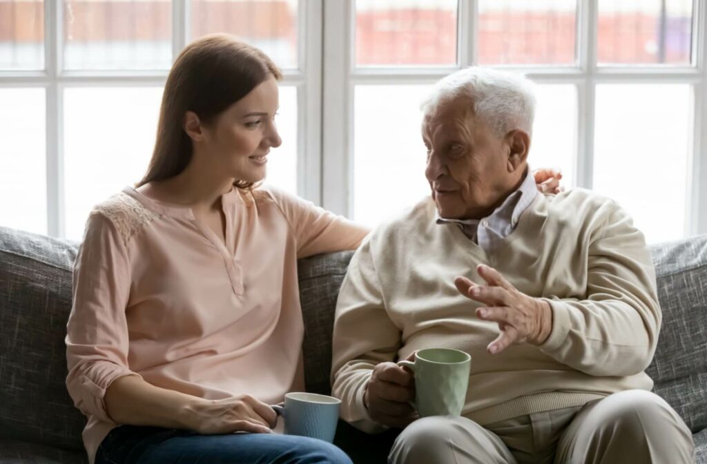 An adult child patiently listens to their parent with dementia, who is sharing something with them.