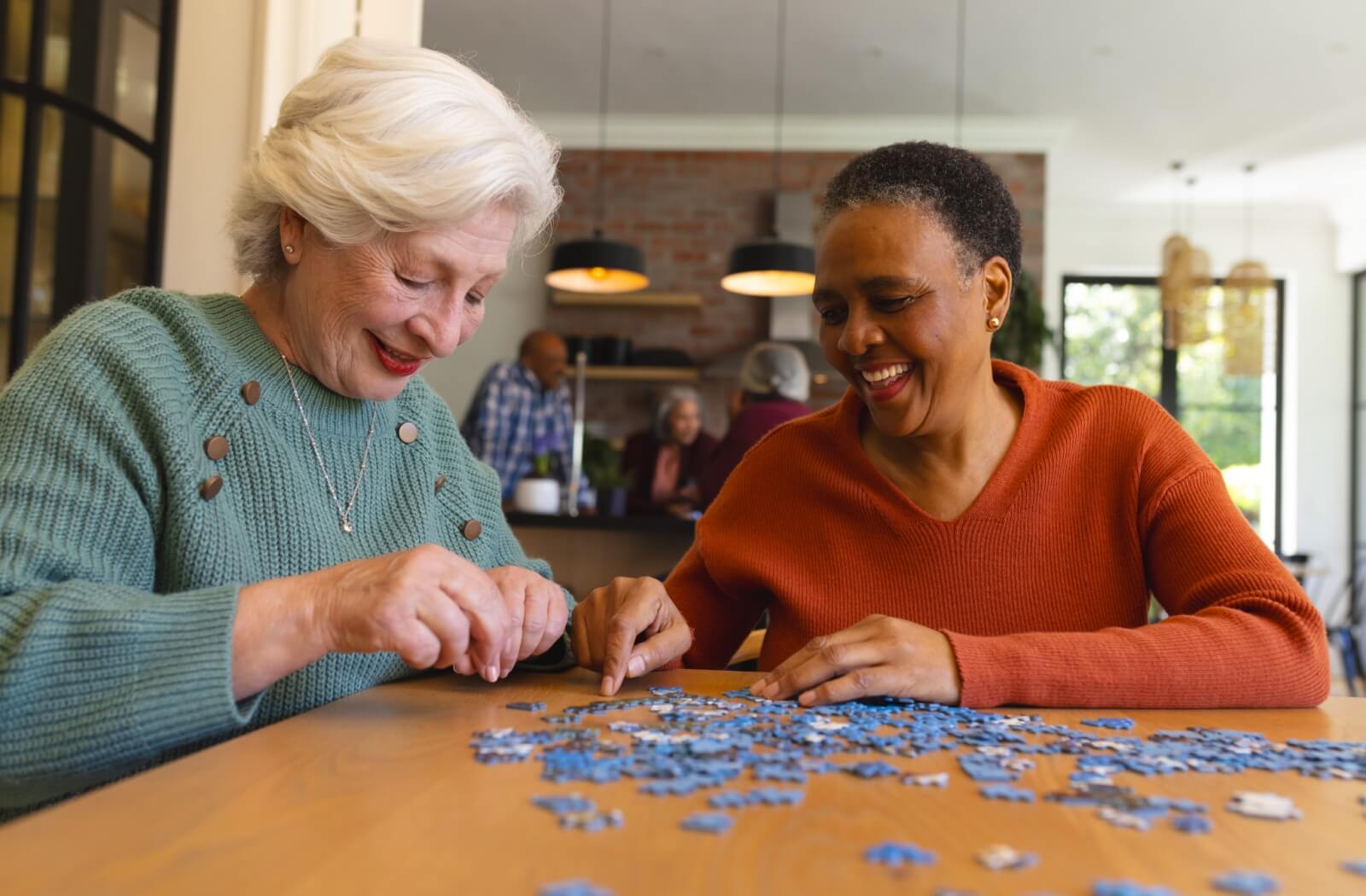 A pair of seniors enjoying piecing together a puzzle in memory care.