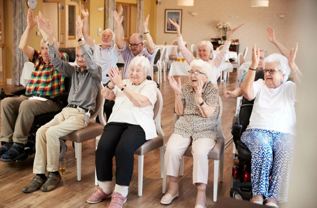 A group of happy seniors clapping their hands and celebrating together during an assisted living activity.