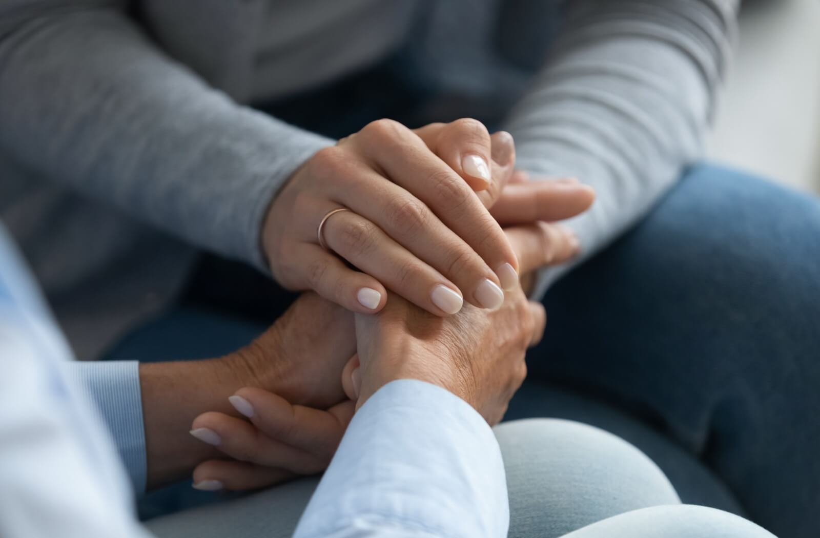 An adult child clasps their older loved one's hands together to reassure them about their recent memory loss and Alzheimer's symptoms